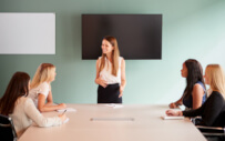 A group of female professionals discuss employment challenges in a meeting.