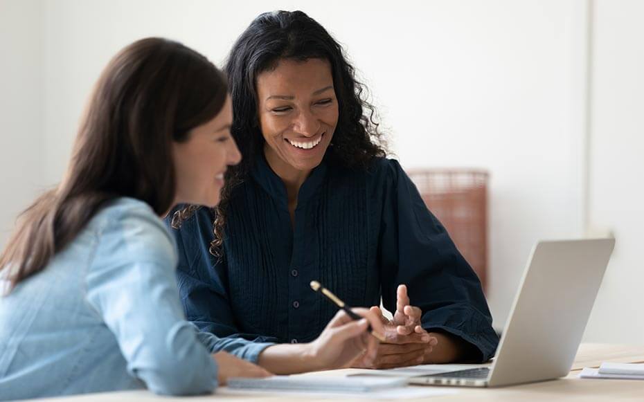 Two women collaborate at a computer.