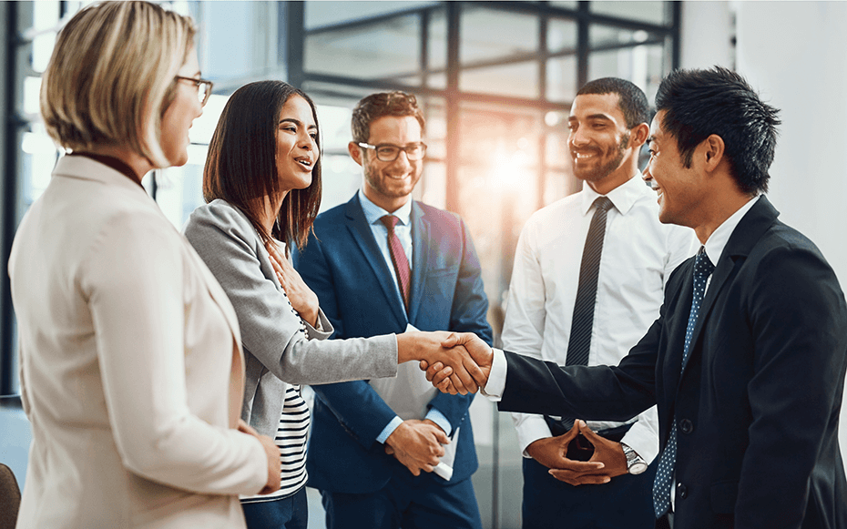 A group of professionals greet a job candidate.