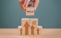 Someone stacking some wooden blocks with a block that says "skills" on top.