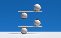 Four rows of stone balls balancing on boards.